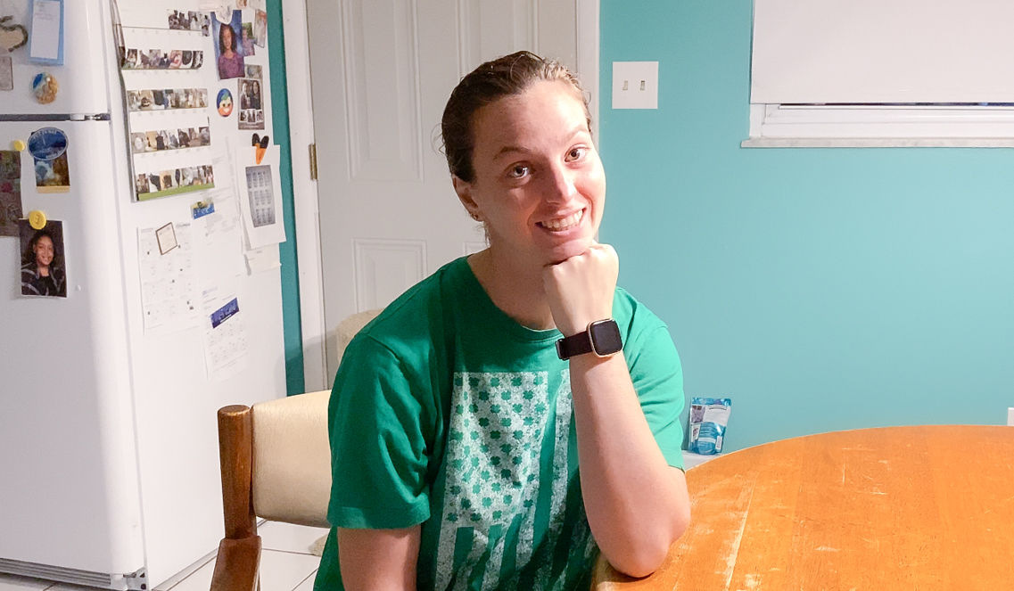 A woman smiling at a kitchen table.